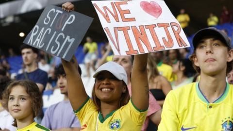 A Brazil fan holds banners in support of Vinicius Jr during their friendly with Guinea