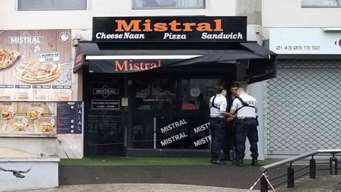 Police stand in front of the shop where a waiter was shot dead by a customer allegedly angry at having to wait for a sandwich, in the eastern Paris suburb of Noisy-le-Grand on August 17, 2019