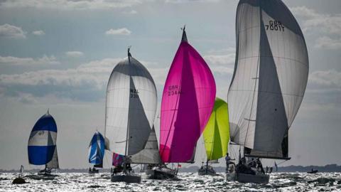 A group of yachts on the sea with different coloured billowing sails. They include Challenger, Nimbus, Salt.
