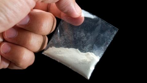 Generic image showing a close up of a hand holding a small clear bag with white powder inside