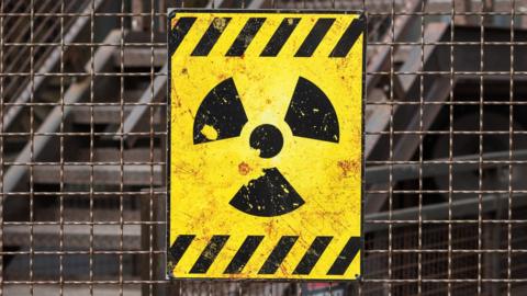 Radioactive warning sign on rusty fence