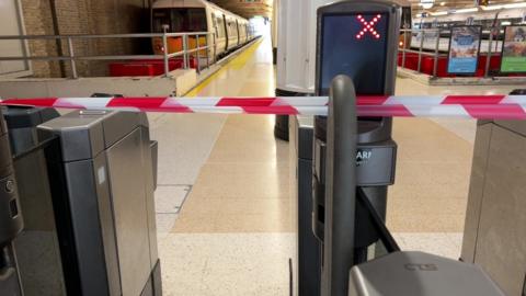 Charing Cross ticket barrier with red cross and red tape