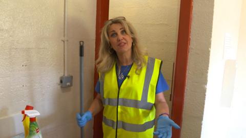 Volunteer standing with mop cleaning toilets