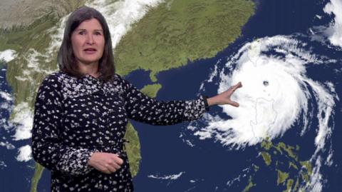 Helen Willetts in front of a satellite image of Typhoon Krathon