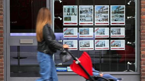 A member of the public looks at residential properties displayed for sale in the window of an estate agents' in London on September 30, 2022