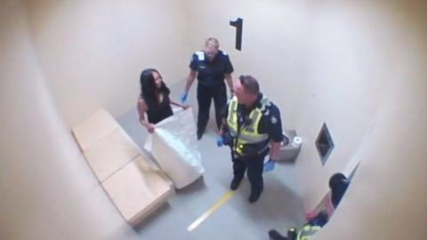 Tanya Day stands in a cell with police officers