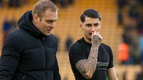 Norwich City boss Johannes Hoff Thorup talks to striker Borja Sainz as they walk along the touchline