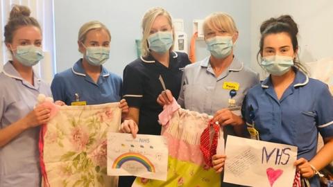 Midwife Vicki Hill (centre) with NHS staff holding the bags