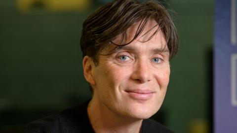 Cillian Murphy, wearing a black top and smiling towards the camera