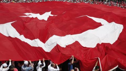 People carry a large Turkish flag