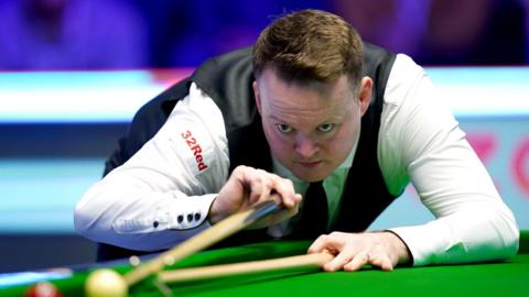 Shaun Murphy leans over the table and cues up a shot