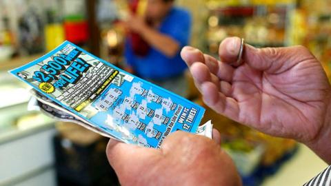 A man uses a quarter and scratches to reveal if he's won a prize on a scratch card