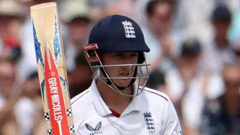 England batter Harry Brooks raises his bat after hitting fifty