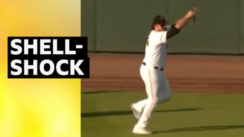 Baseball player holds up a turtle that invaded the pitcg