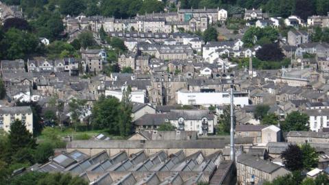 View looking west from Castle Hill in Kendal. There are hundreds of houses among some greenery.