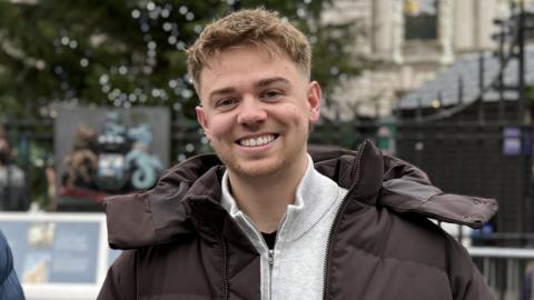 Man in brown puffer coat smiling at camera
