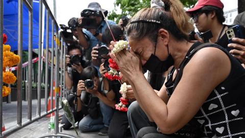 A woman prays for her deceased daughter and her son-in-law Suwitcha Sirililung in front of the Rong Beer Na Lat Phrao bar in Bangkok on July 14, 2026.