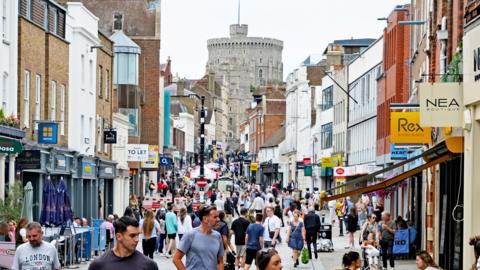 Peascod Street, Windsor, Berkshire, United Kingdom, August 16, 2025. Busy pedestrian shopping street. Windsor Castle in background. Overcast summer day outdoors.