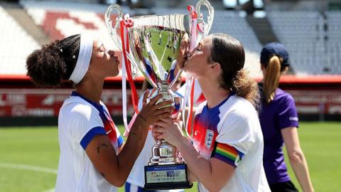 Lenna Gunning-Williams and captain Ruby Mace kiss the trophy