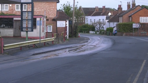 A water leak coming from a road and running downhill.
