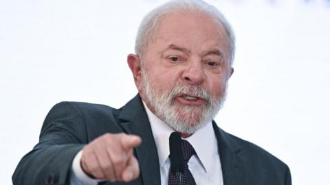 President Lula, wearing a navy blue suit and a dark tie, points at something while speaking at Planalto Palace in Brasilia, Brazil, 20 March 2023