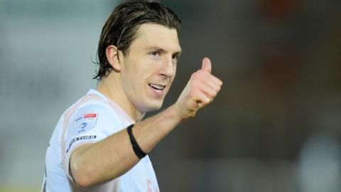 Plymouth Argyle centre-back Alex Mitchell gives a thumbs up signal during a match 
