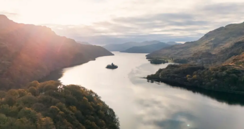 A scenic picture of Loch Lomond with the sun in the background 