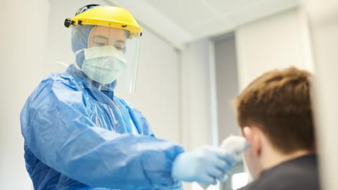 A doctor in protective gear taking a boy's temperature