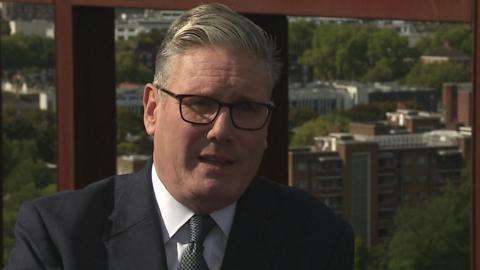 Head and shoulders of Sir Keir Starmer with buildings and trees in the distance behind him
