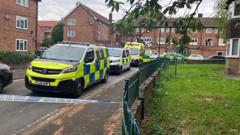 Police vans and ambulances in a cordoned off residential street.