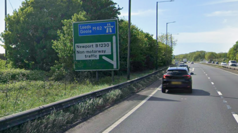Google shot of a slip road exit sign. It is a green with a blue and white motorway sign at the top, directing traffic to Leeds and Goole on the M62. Below, another part of the sign says non-motorway traffic and B1230. 

