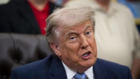 US President Donald Trump sits on a leather chair and speaks