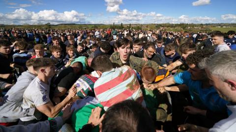 A scrum of people wrestling over a barrel in a field - although the barrel is deep inside the melee and cannot be seen