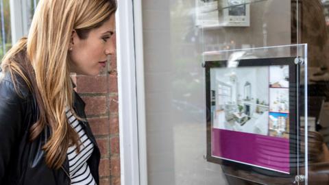 Woman looking into estate agents window