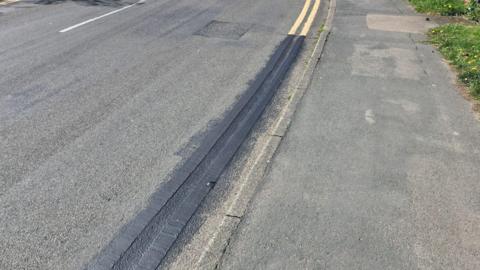 Yellow lines on a village road obscured with black paint 