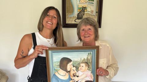 Sophie Cook and Teresa Cook stood holding a painting