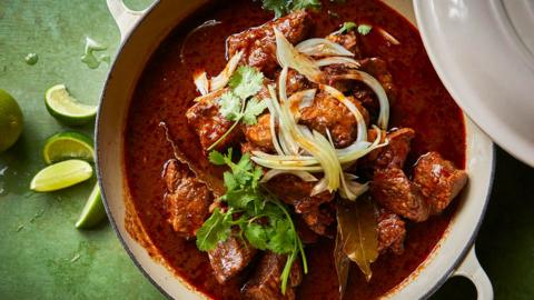 Birria beef in a while pan with a green background