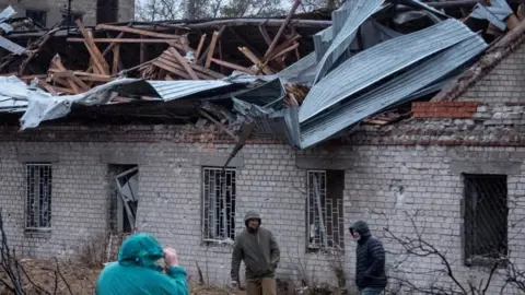  Residents walk at a site of a Russian missile strike, amid Russia's attack on Ukraine, in Dnipro, Ukraine November 21, 