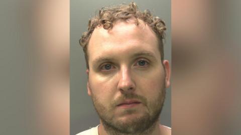 Craig Winston, wearing a white t-shirt. He has short cropped facial hair and curled brown hair