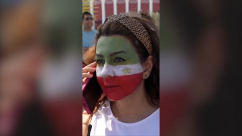 Woman with face painted in green, white and red