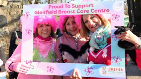 Walkers in pink wearing decorated bras pose with a frame at Bradgate Park, in Leicestershire, in 2024.