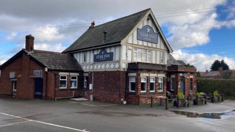 A two-storey building with a car park surrounding it. There is a sign on the upper part of the building which says 'Star Inn'.