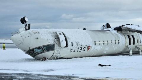 The wreckage of a crashed Delta Air Lines plane on a snowy runway