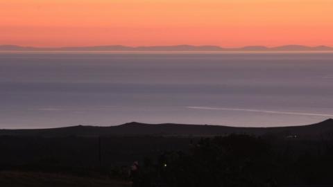 Llun maint llawn: Mynyddoedd Wicklow a'r tonnau'n torri ar draeth Dinas Dinlle o Groeslon