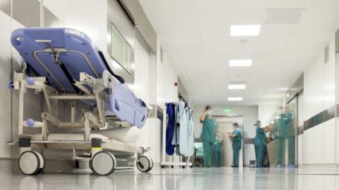 Generic image showing a hospital trolley, with nursing staff in the background