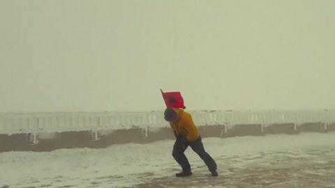 Man carrying flag in high winds