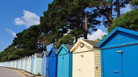 Blue skies above colourful beach huts in Mudeford, Dorset, on 26 June 2023
