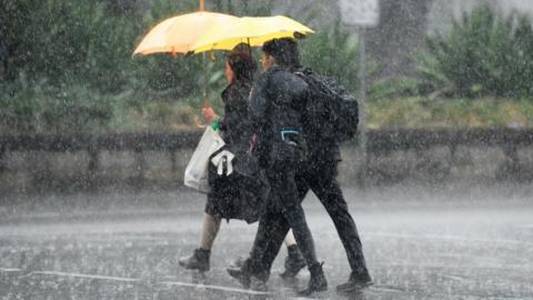 Pedestrians hold umbrellas as they walk in heavy rain in Sydney on 17 January 2020.