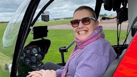 Krys Kemple in a helicopter, smiling