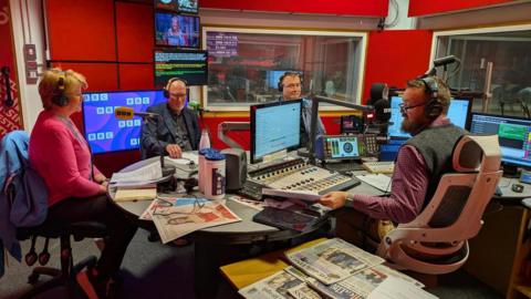 Three politicians sat in a radio studio opposite the presenter.